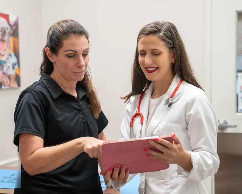 Dr. Kerrie Lewis reviewing an anesthesia plan on a tablet with a veterinary practice manager